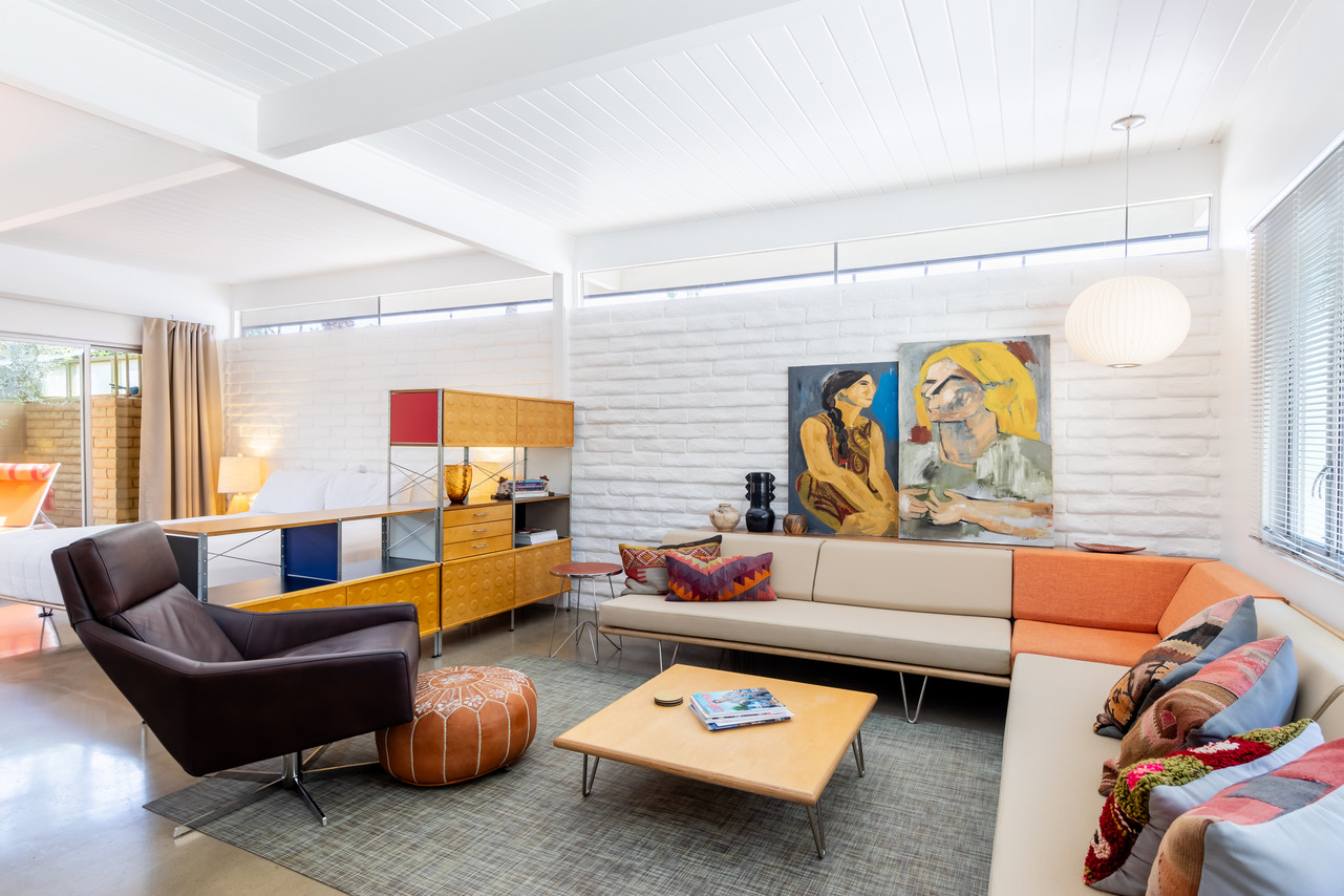 A modern lobby with a sectional sofa, armchair, coffee table, and artwork on the walls.
