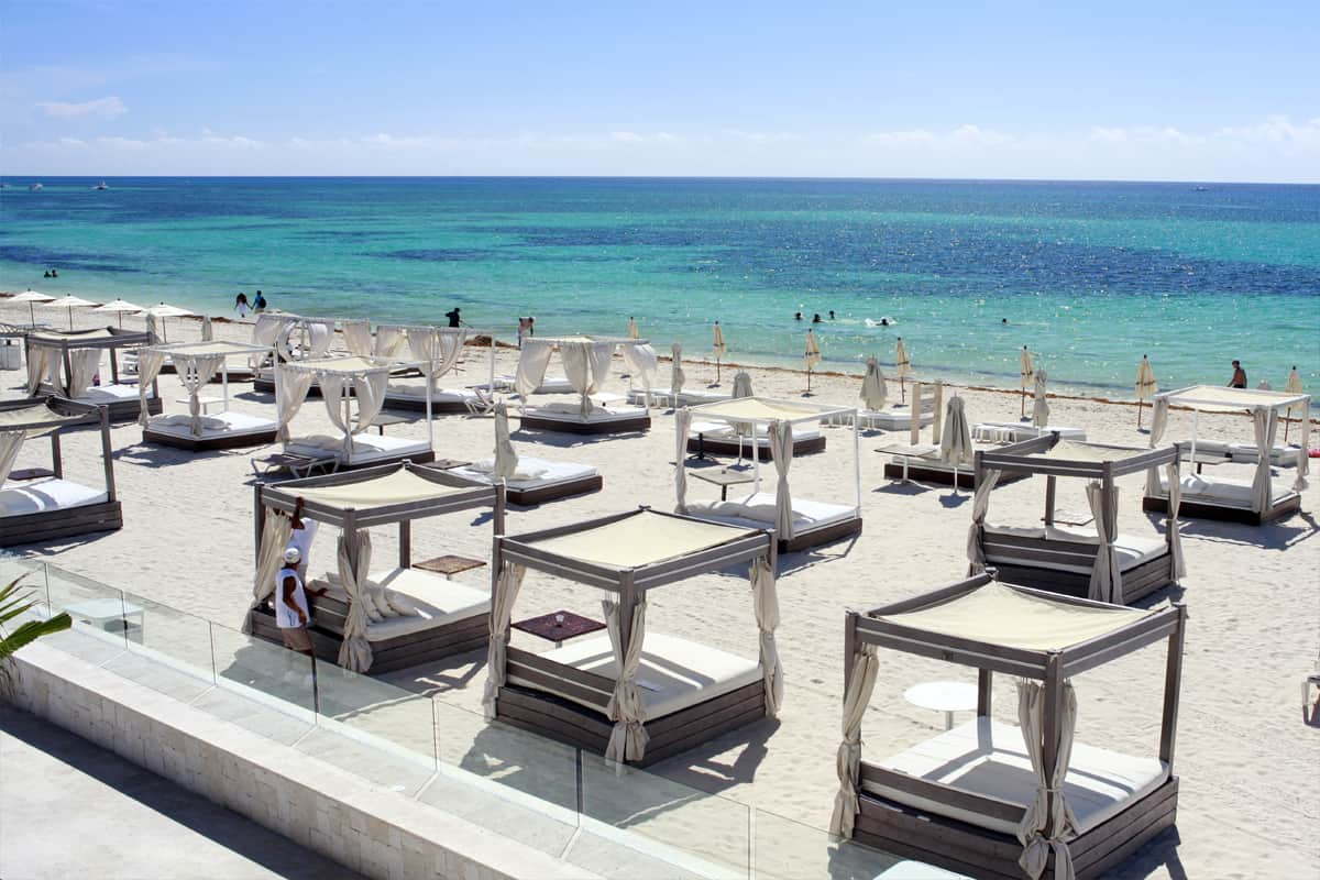 Daybeds and turquoise water at a beach club in Playa del Carmen
