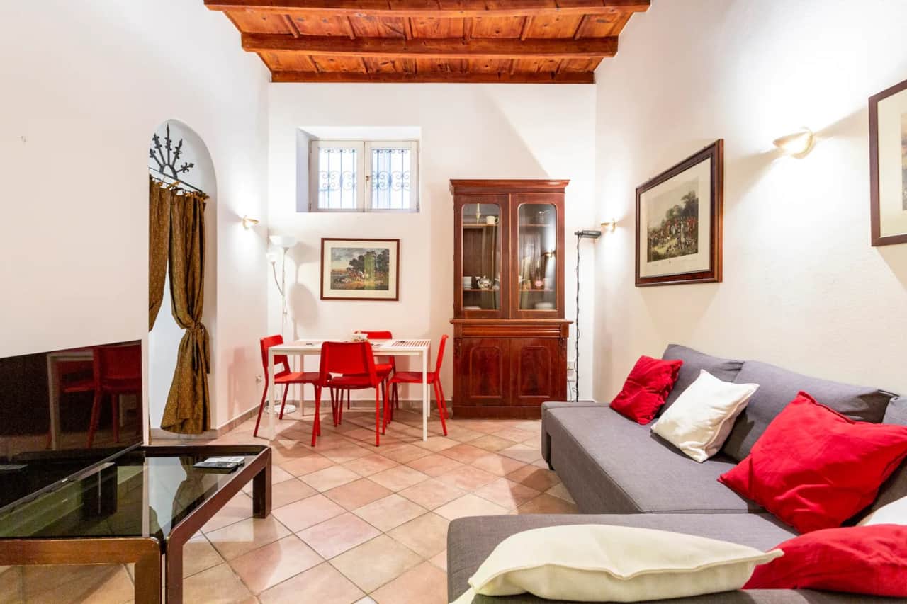 Wohnzimmer mit grauem Sofa, Küche und Balkendecke, in Mailand