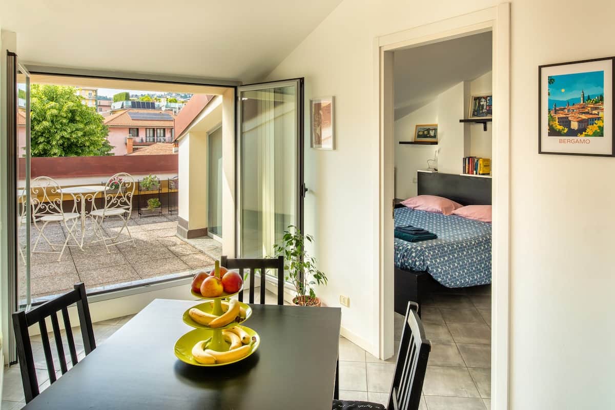 Una panoramica degli spazi: la zona pranzo si apre verso la luminosità della terrazza, mentre uno scorcio sulla camera da letto mostra la continuità e la comodità del layout.