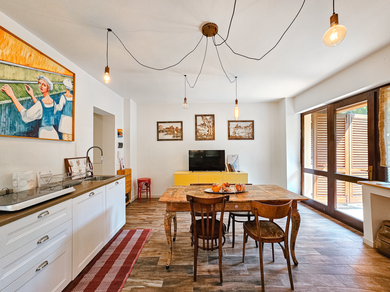 Il soggiorno open space con cucina, tavolo e TV