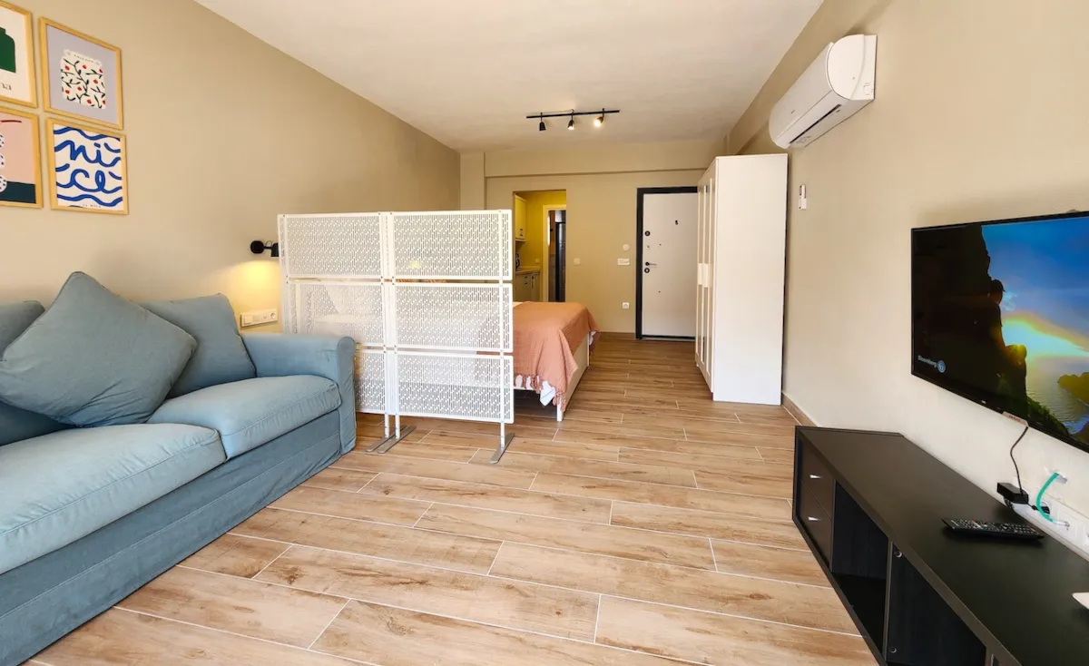 Living area with a blue sofa, partition, and a TV, Apart Guney 8, Gocek