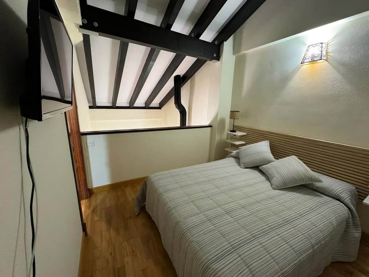 Dormitorio principal con cama de matrimonio y techo de vigas