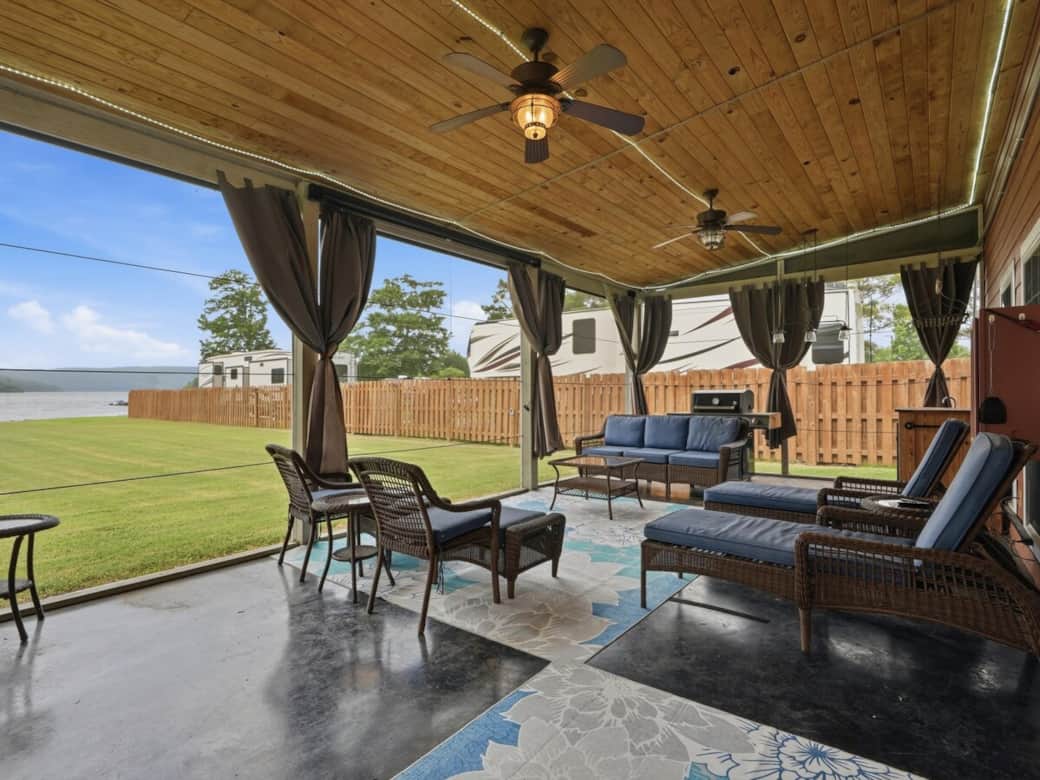 Enjoy the covered, screened-in back porch featuring a pull-down screen, projector, sound system, hot tub, towel warmer, grill, sink, and mini fridge—perfect for entertaining, relaxing, and enjoying your stay. 