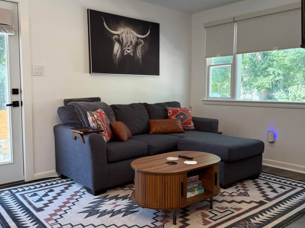 This living room is pure Southwest-cozy. Stretch out on the deep sectional, sip something warm, and admire that handsome highland cow watching over you. Between the bold rug, cozy pillows, and soft light, you may never want to leave this corner.
