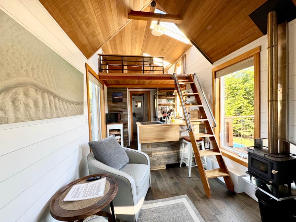 Living area with custom ladder to the bedroom loft and wood burning fireplace 