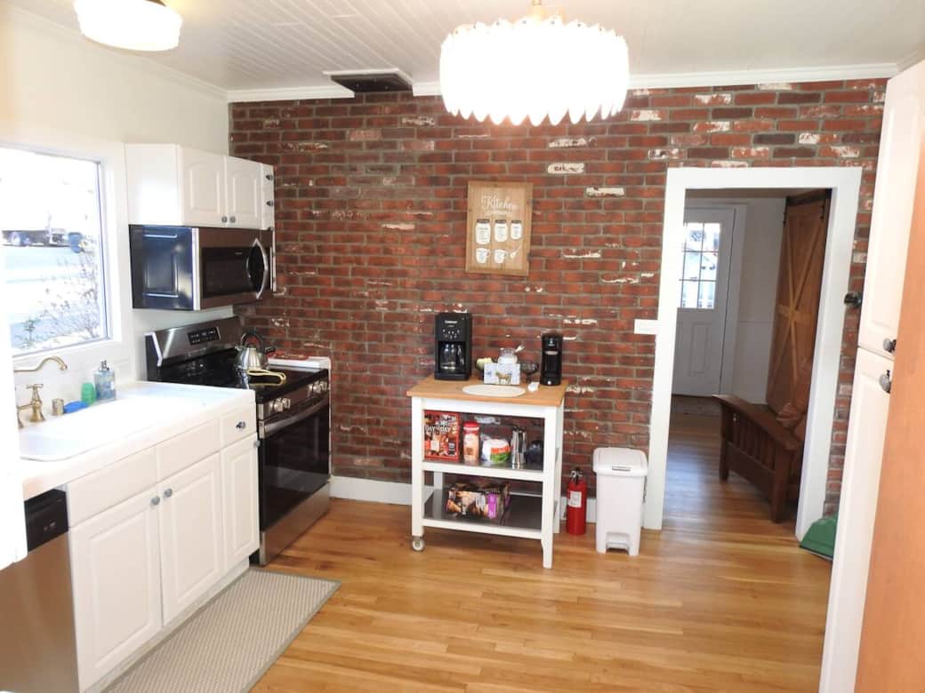 Kitchen with electric stove, microwave and coffee cart
