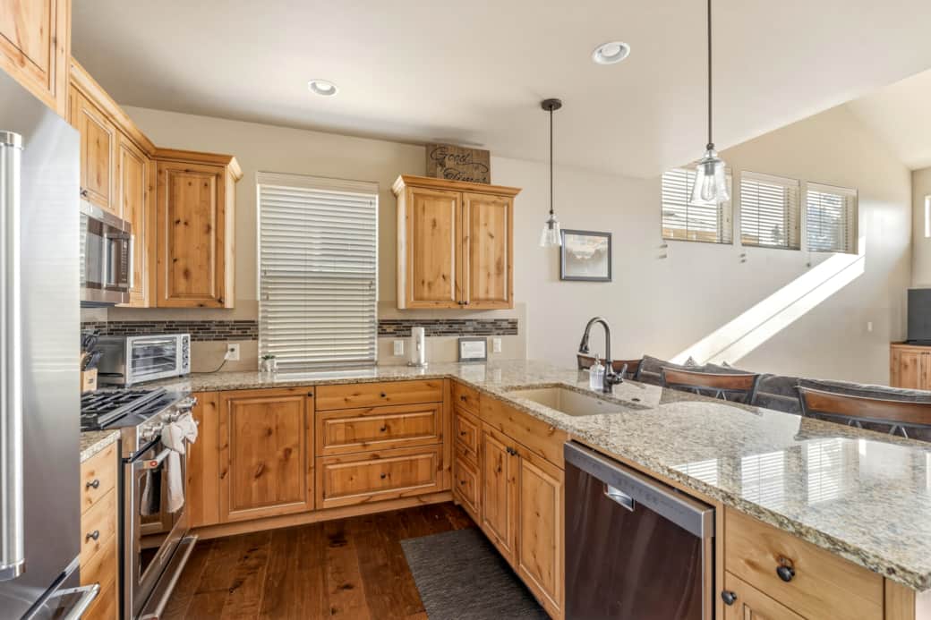 KitchenAid gas range, tile backsplash, and L-shaped layout with full stainless appliance suite.