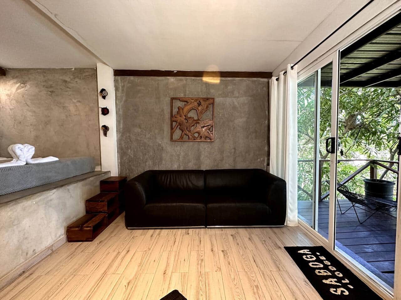 Sitting area with a black sofa and carved wood art, opening to the deck at Saboga Lodge
