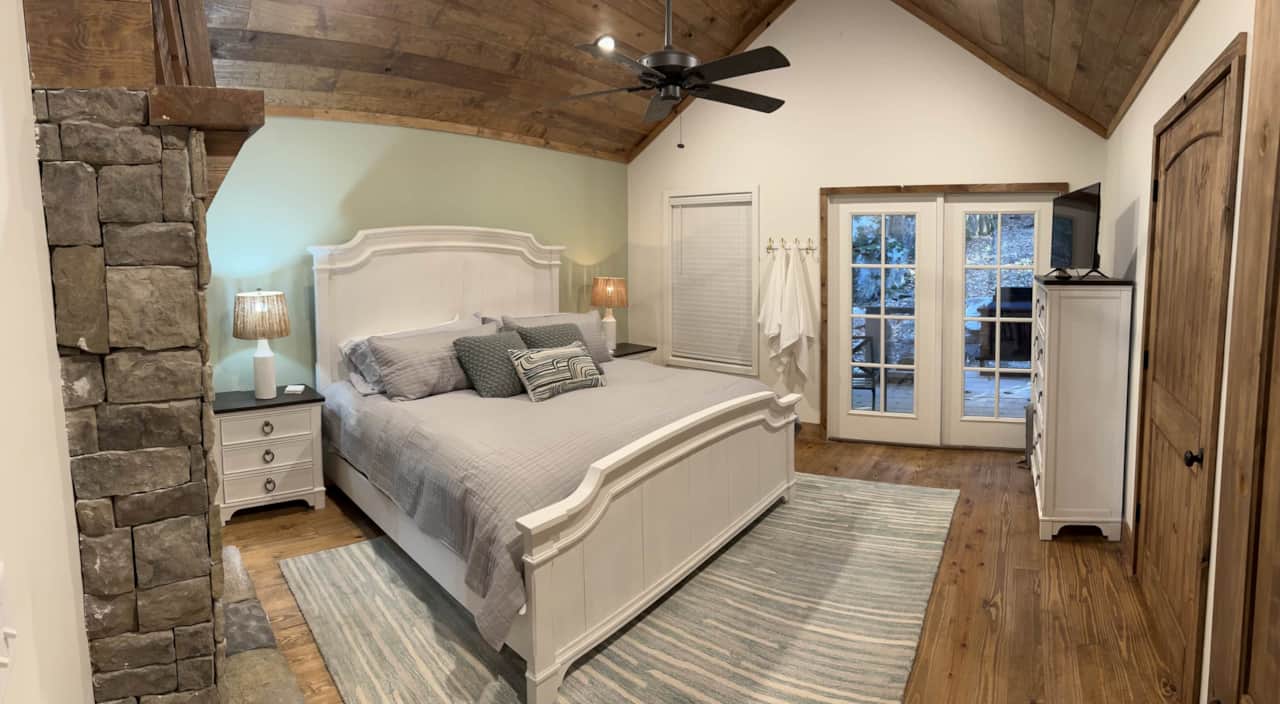 Bedroom opens to back deck with outdoor fireplace, hot tub