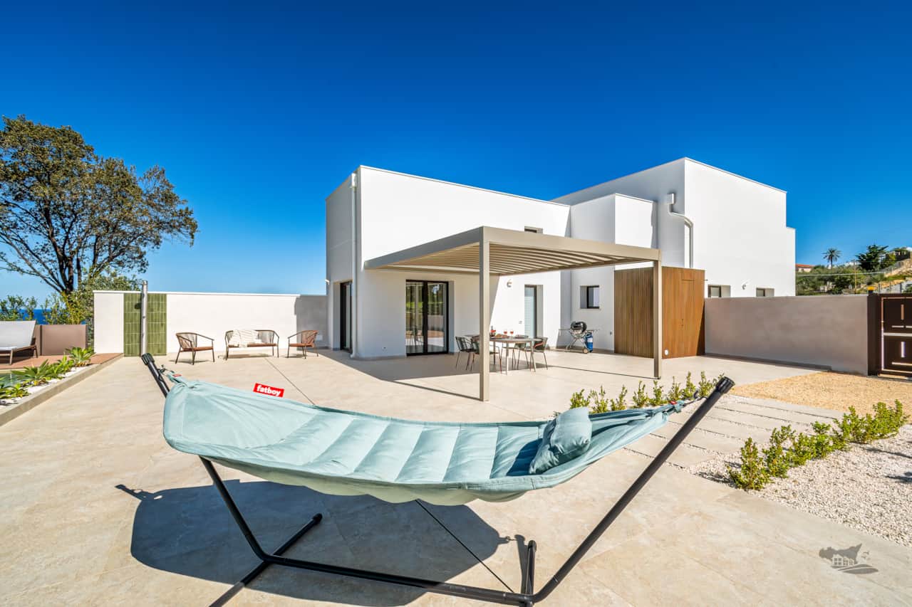 Modern outdoor area with hammock, shaded dining pergola, BBQ, and wide open space to relax.