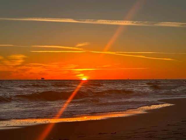 Breathtaking view of the Gulf Shores beach at sunset, with golden skies reflecting on the water