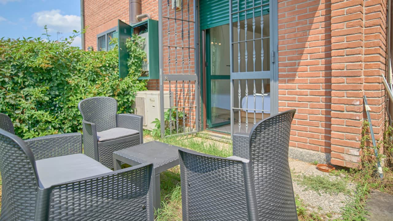 Garden terrace with chairs and small sofa in front of the house