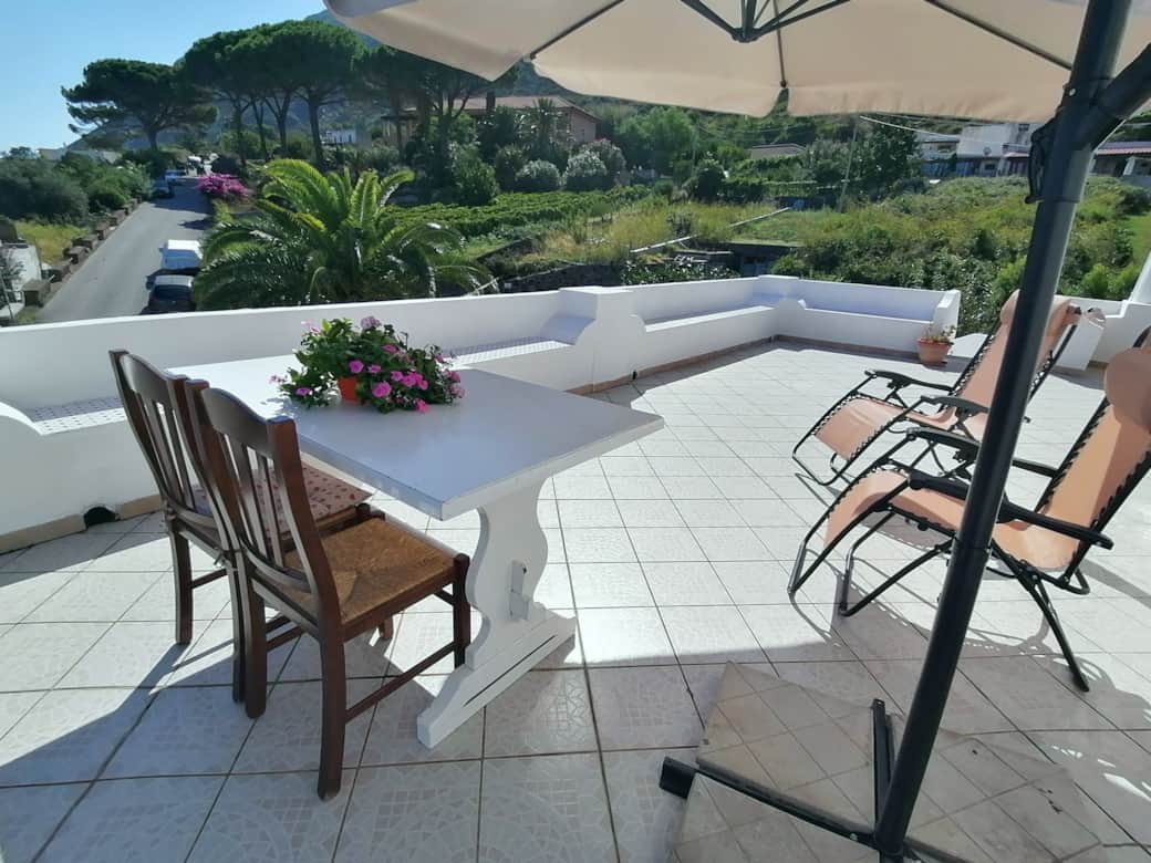 Terrazza panoramica di Casa Zagami a Malfa, isola di Salina, con sdraio e vista sul verde