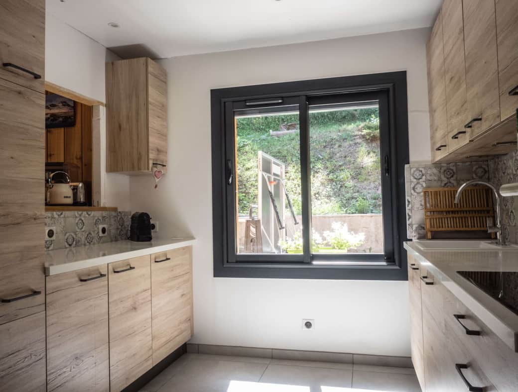 Cuisine entièrement équipée avec passe plats et vue sur le jardin et le ping pong