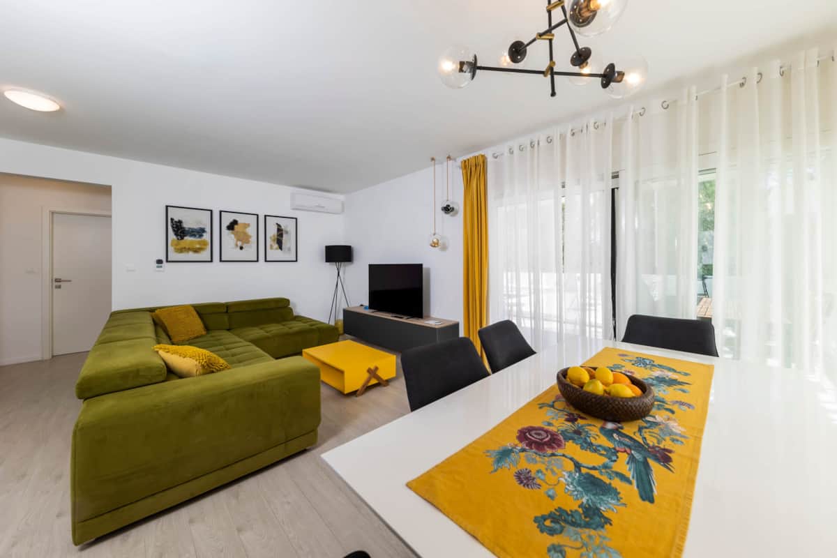Bright living room with green sofa and dining table