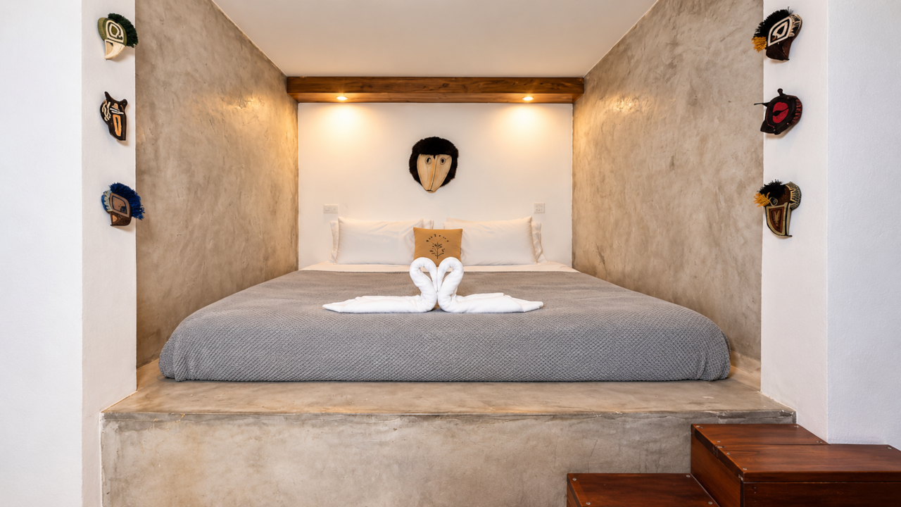 Alcove bed on a raised concrete platform framed by masks, suite at Saboga Lodge, Panama