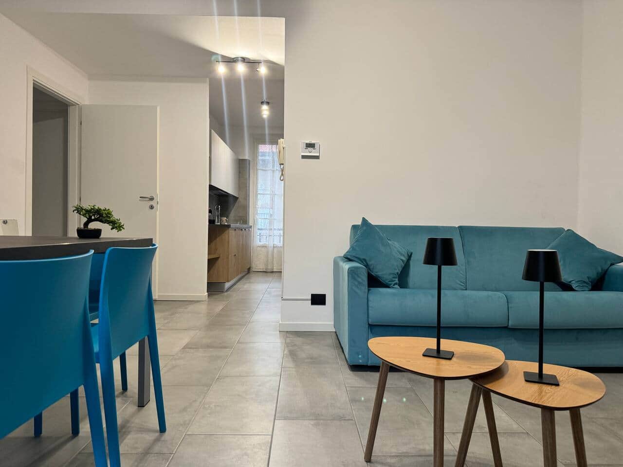 Salotto moderno e luminoso, con divano blu ed elementi in legno che creano un’atmosfera calda e rilassante, completo di Smart TV e zona pranzo integrata.