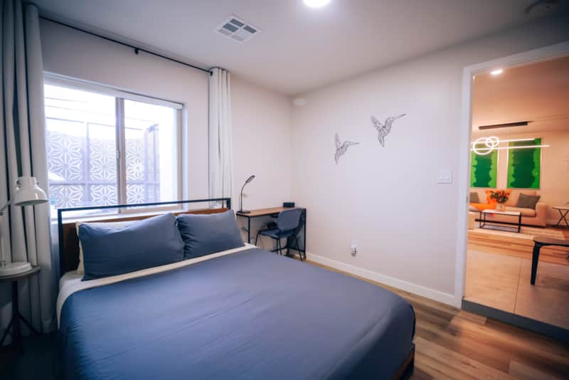 Queen bedroom with a desk, window and mirrored closet.