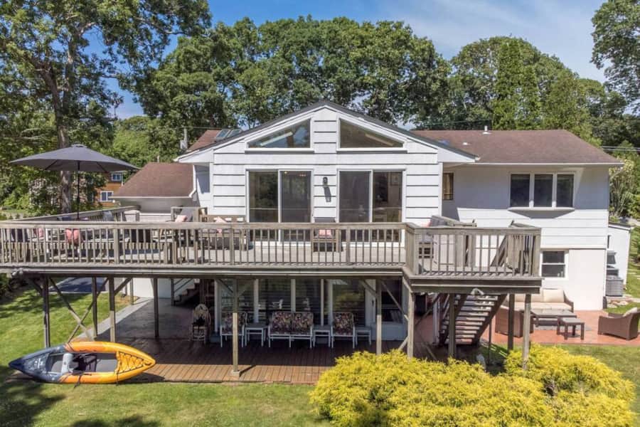 The back of the house from the lawn, with the deck above and a kayak on the grass