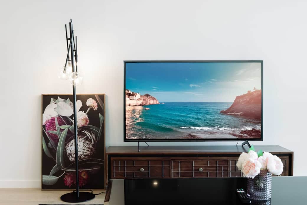 The TV area is designed for entertainment and relaxation. A large flat-screen TV is the focal point, flanked by a stylish media console and decorative accents. The wall art adds a touch of sophistication,  the vase with flowers brings a beauty.