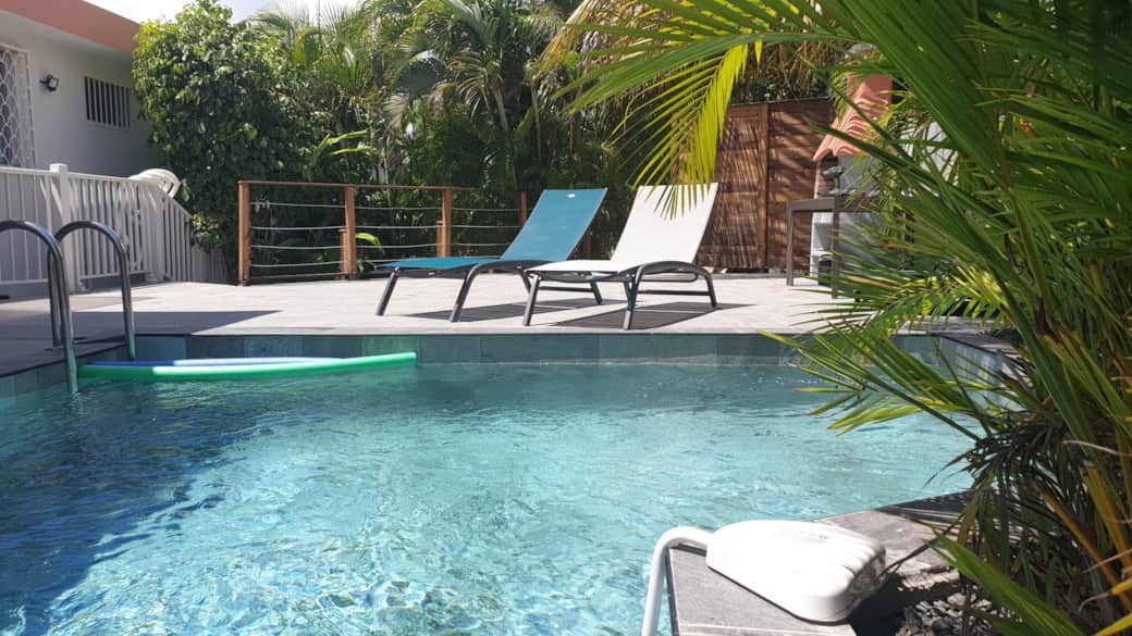 Bord de piscine avec transats et végétation luxuriante - Villa ZEINGA SAINTE ANNE Bord de piscine avec transats et végétation luxuriante - Villa ZEINGA SAINTE ANNE
