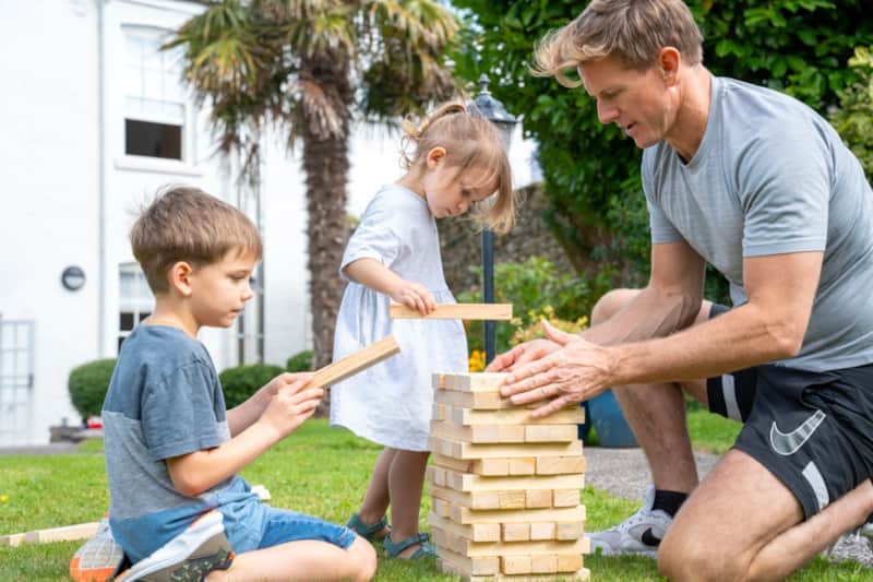 A family playing giant Jenga on the lawn