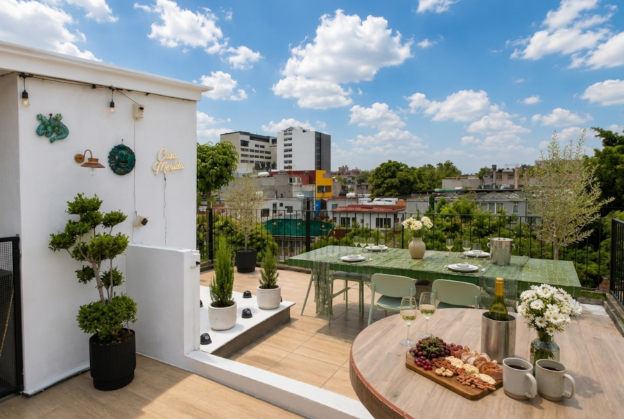 Terraza privada de Casa M&eacute;rida con mesa puesta sobre los techos de Roma Norte