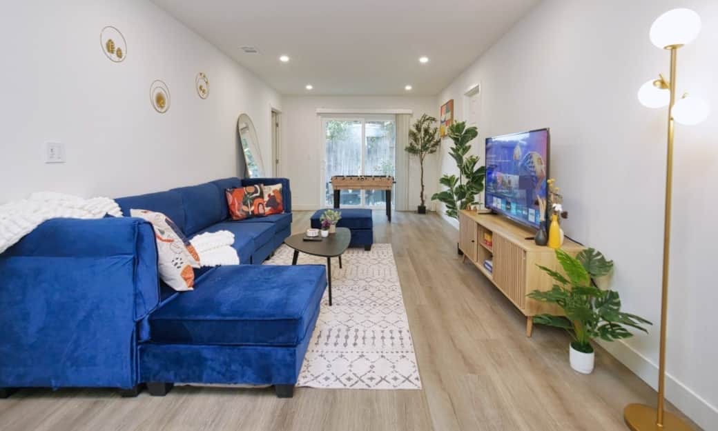 Sleek living room with comfortable seating, large TV, and a foosball table for entertainment. Sleek living room with comfortable seating, large TV, and a foosball table for entertainment.