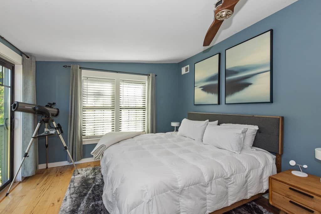 Serene bedroom with king bed, telescope, and calming blue decor