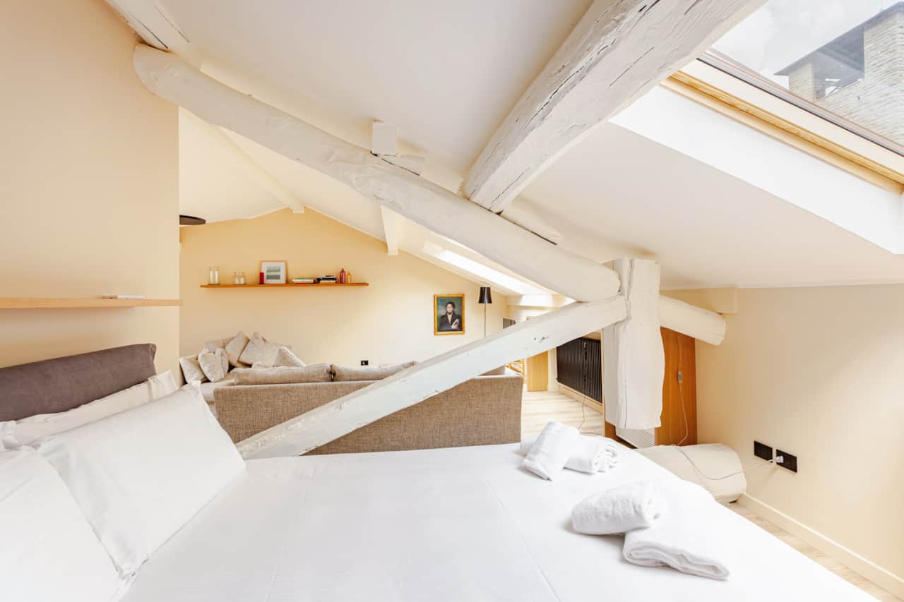 Schlafzimmer mit weißem Bett unter der Dachschräge