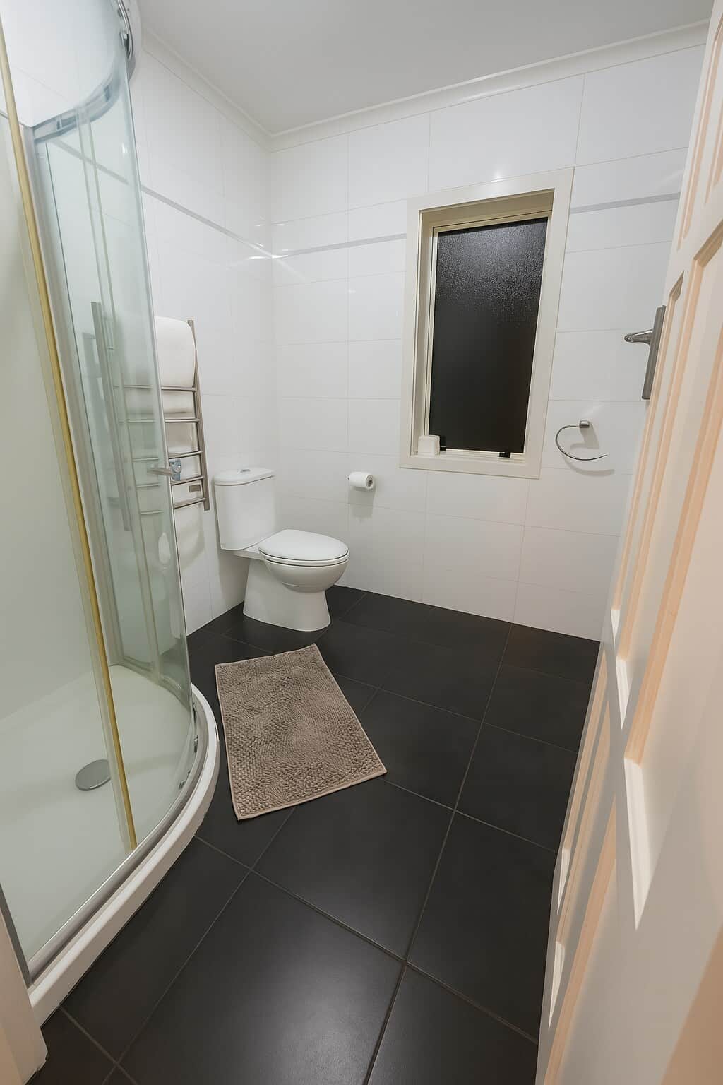 This bright and functional main bathroom features a sleek glass shower, modern toilet, and heated towel rail for added comfort