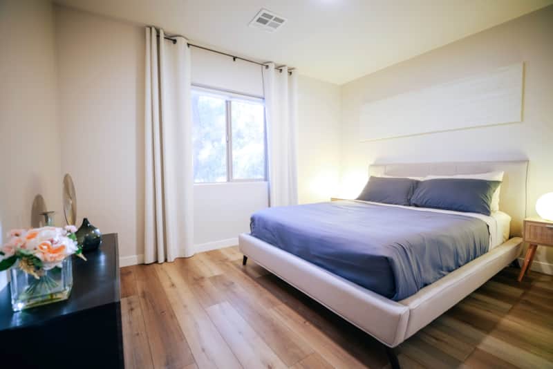 Queen bedroom with two windows and bedside storage.