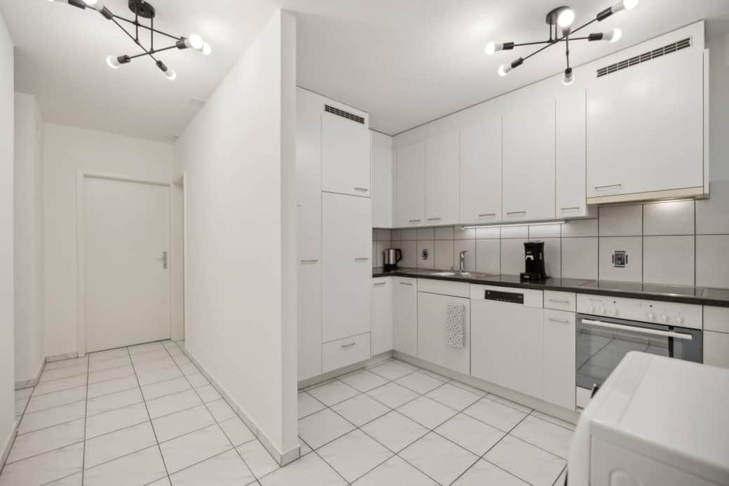 Wide view of the hallway and full kitchen with tons of cupboard space and light.