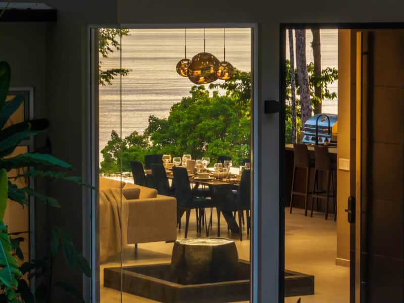 Private dining table at Villa Sueño Costa Rica, set with candles and overlooking the Pacific Ocean through open doors