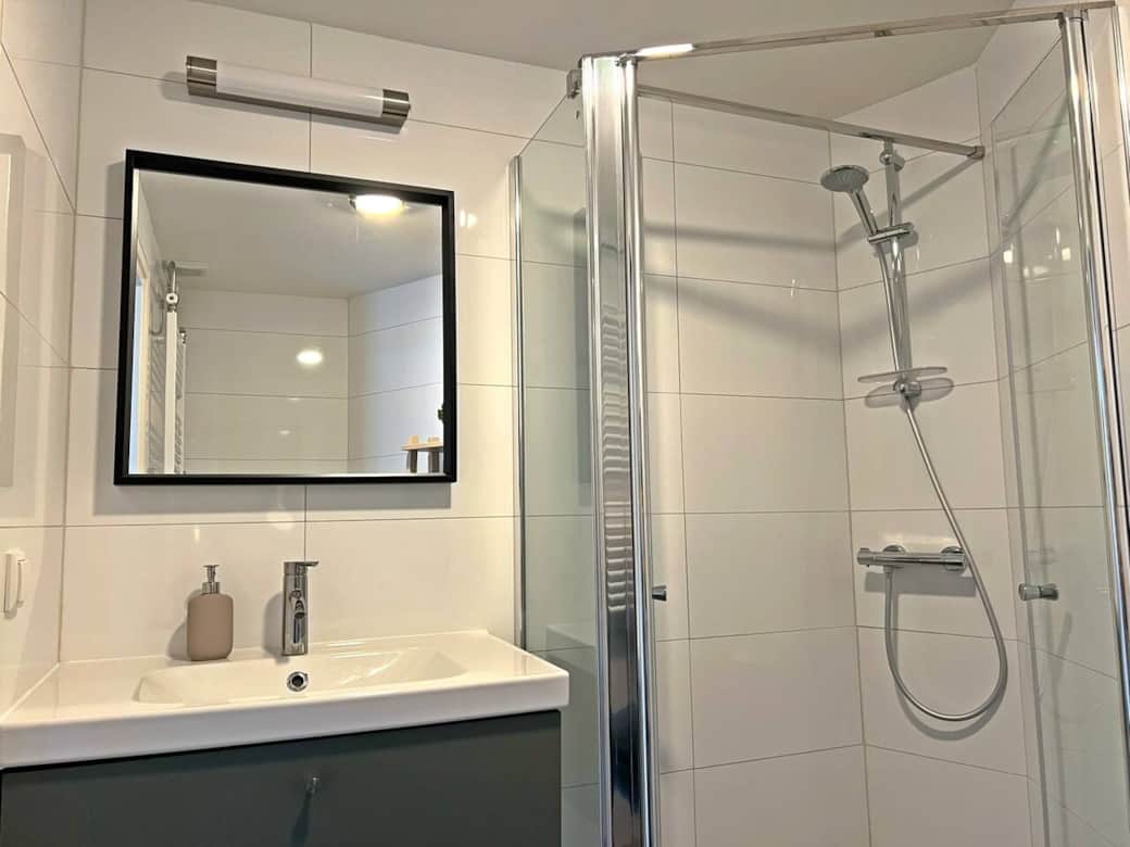 Badkamer met wastafel, douche en een zeeppompje met zeep. Badkamer met wastafel, douche en een zeeppompje met zeep.