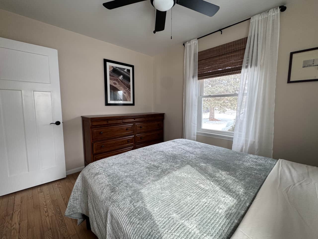 Bright corner bedroom with large windows, soft natural light, and comfortable bedding.