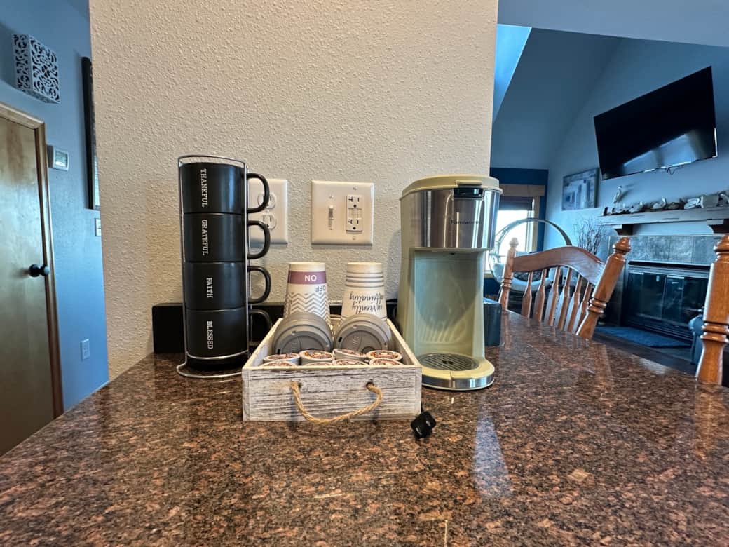 Cozy coffee station, featuring a K-Cup coffee maker and a selection of pods to get you started. Cozy coffee station, featuring a K-Cup coffee maker and a selection of pods to get you started.