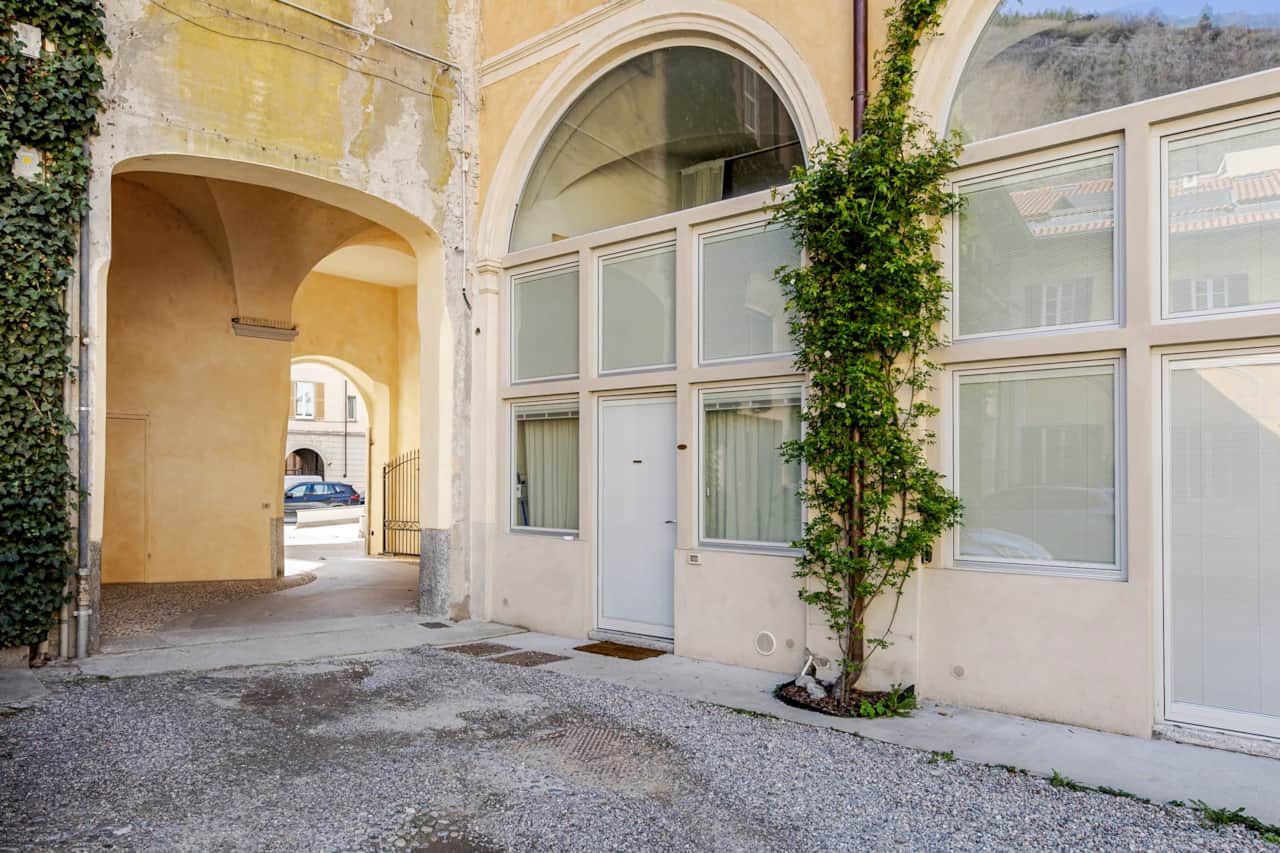 Innenhof mit gelben Bögen und Kletterpflanzen an den Fassaden, in Como