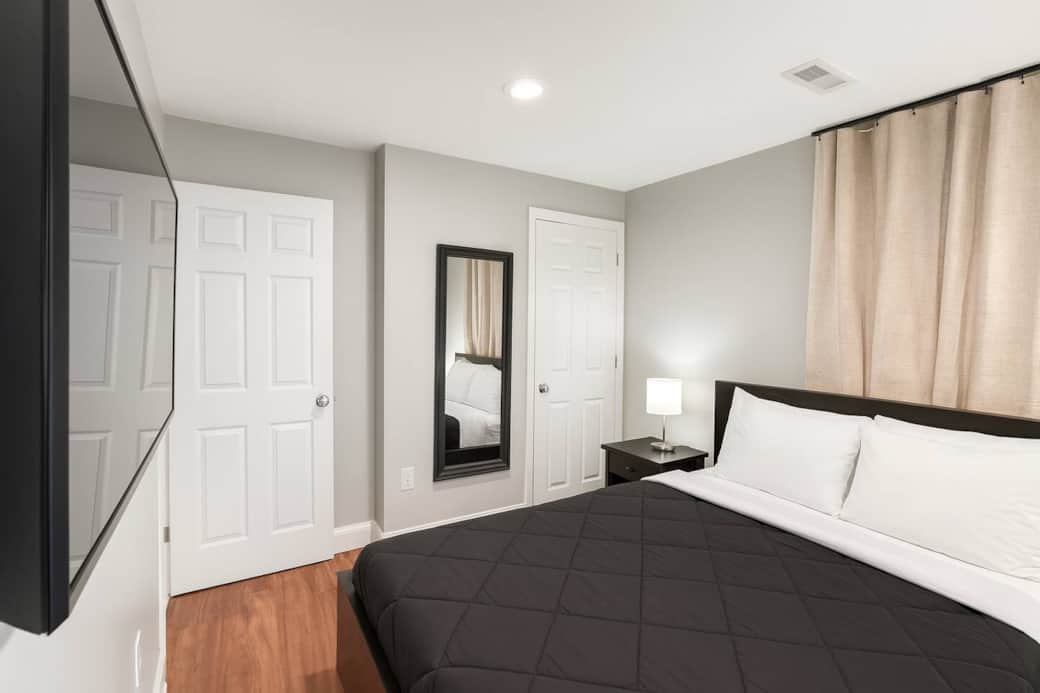 This inviting bedroom features a queen-sized bed, a flat-screen TV, blackout curtains, a side table, a well-lit mirror ,USB charging capabilities, a lamp, and a generously sized closet to accommodate all your storage requirements.