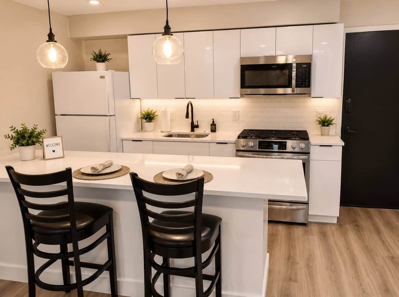 kitchen featuring sleek white cabinetry, stainless steel appliances, a spacious quartz island with seating, and everything you need to prepare meals. Whether you’re enjoying your morning coffee or cooking dinner, this stylish is perfect.