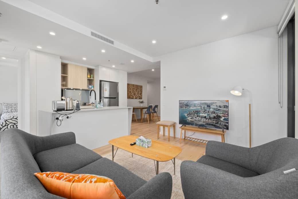 Relax in the inviting living space, featuring stylish furniture, a smart TV, and a seamless flow into the modern kitchen. Whether you're lounging or dining, this open-plan layout ensures a comfortable stay.
