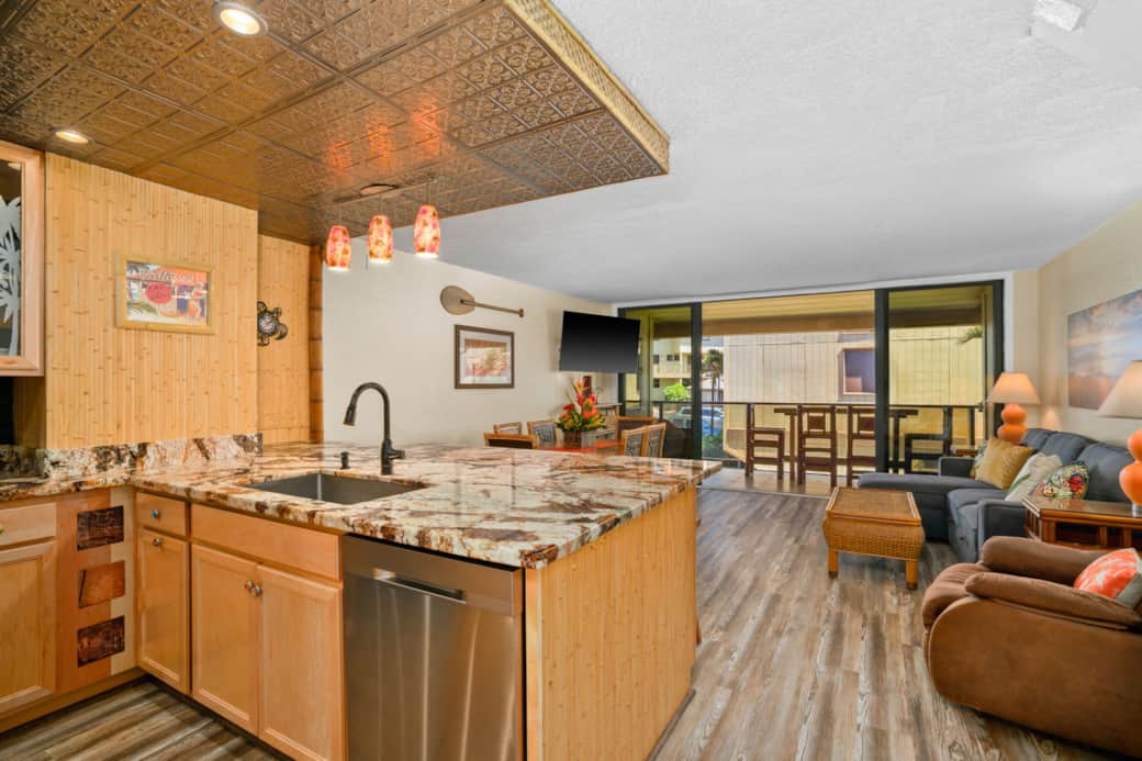 Open kitchen with granite island, flowing into cozy living area and lanai seating.