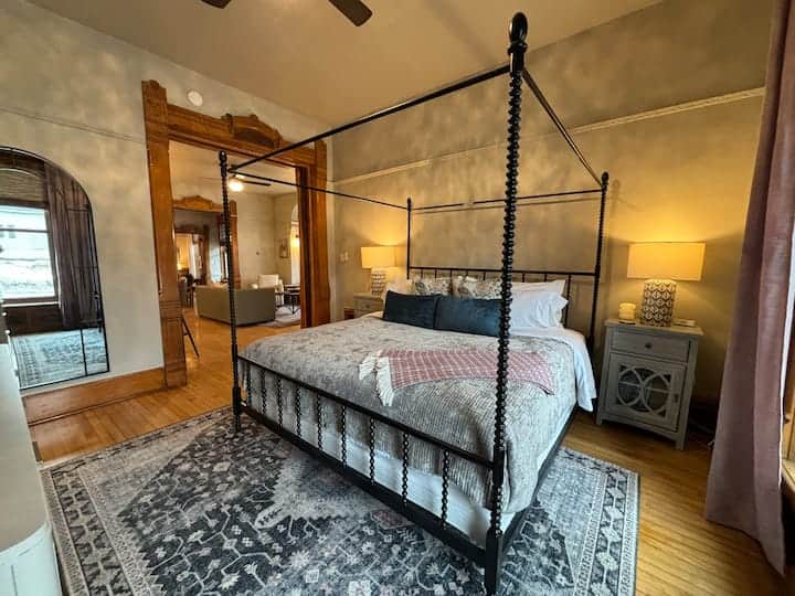 Spacious primary bedroom featuring a stunning four-poster bed, warm ambient lighting Spacious primary bedroom featuring a stunning four-poster bed, warm ambient lighting