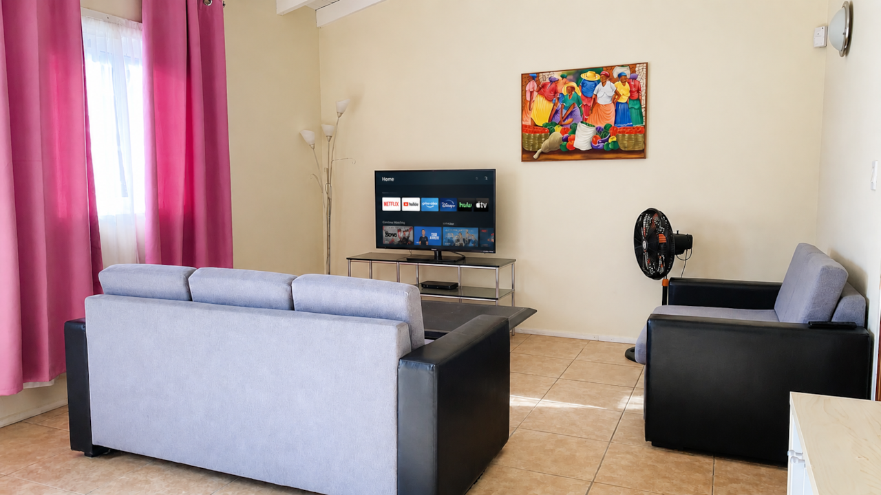 Bright and spacious living room with 5 persons sofa set, fan and a smart tv