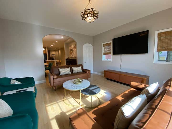 Features comfortable seating, a large wall-mounted TV, and an open flow into the dining space.