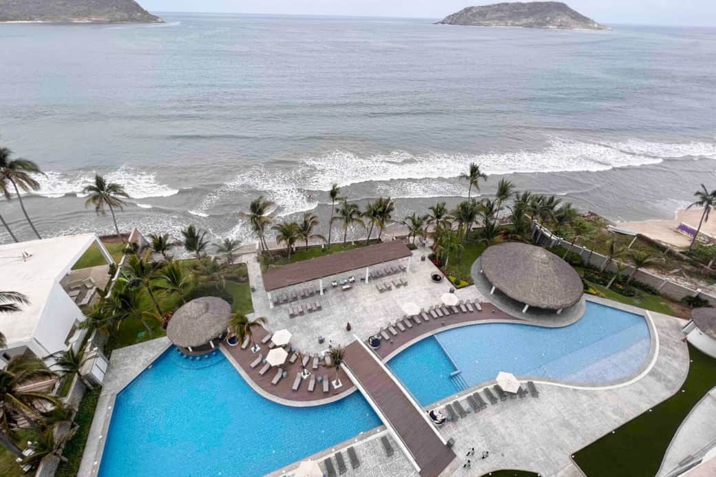 Alberca de lujo frente al mar en Península Mazatlán: área lounge, palapas y playa.