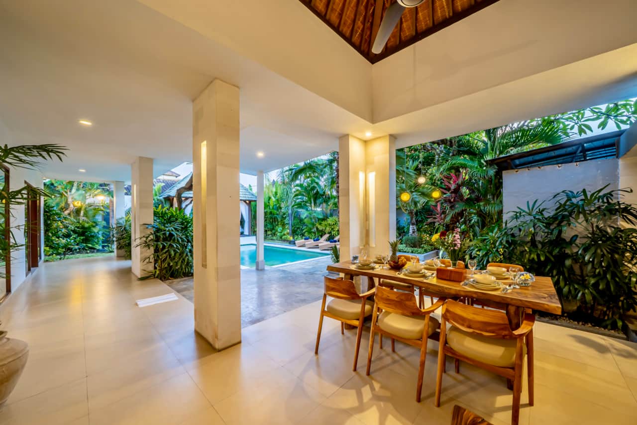 A covered outdoor dining area overlooking the garden and pool.