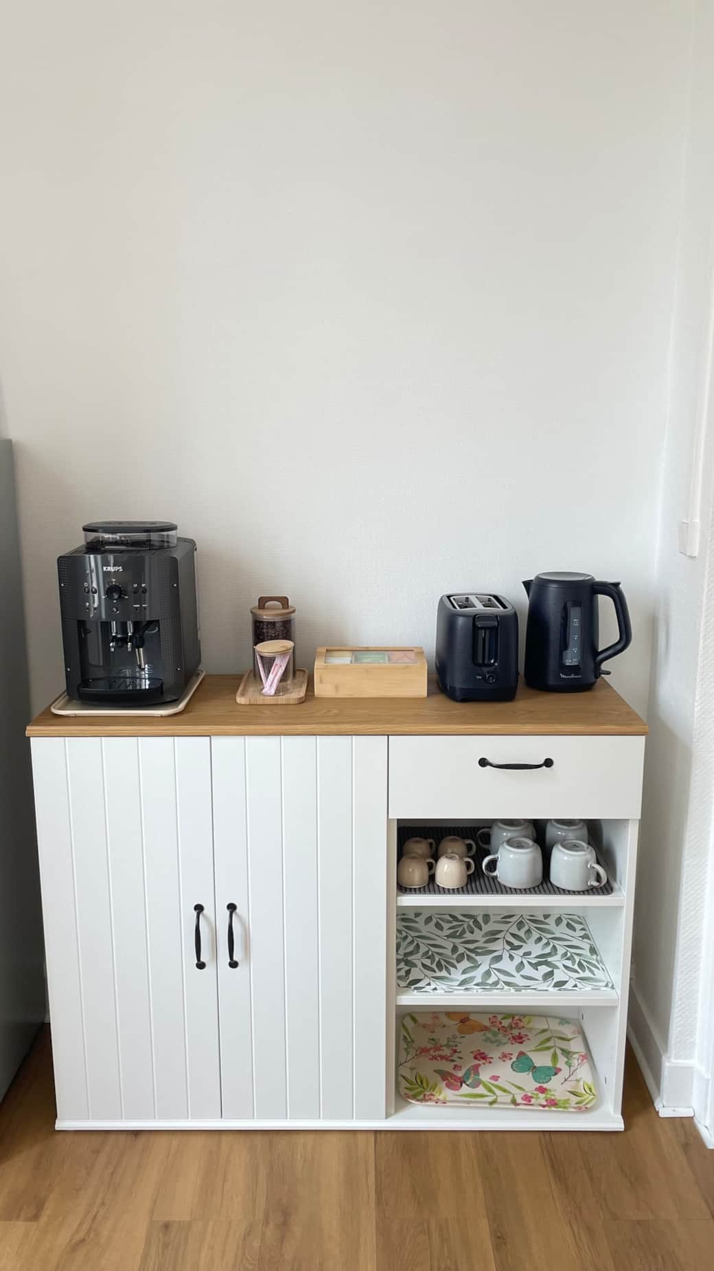 Coin petit-déjeuner équipé : machine à café KRUPS à grains, bouilloire, grille-pain, café, sucre, sélection de thés et tisanes, tasses assorties, plateaux, cuillères et accessoires pour un réveil gourmand et pratique.