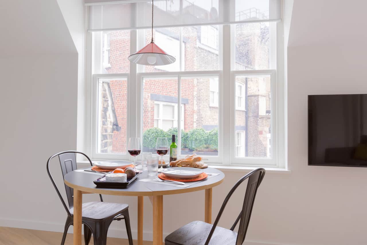 Round dining table by the window, set with wine and fresh bread